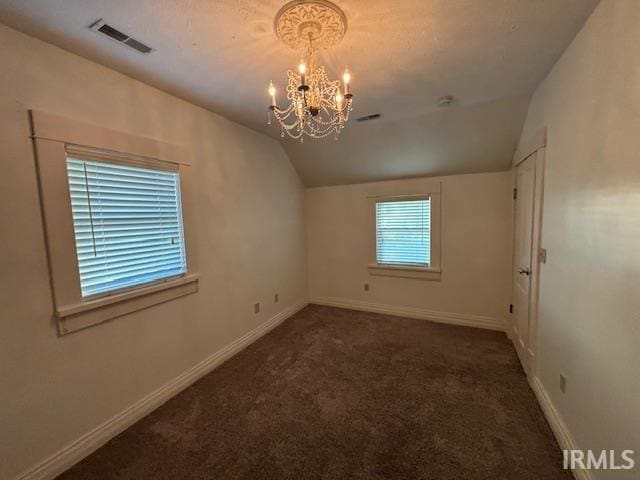 carpeted empty room featuring a chandelier and vaulted ceiling