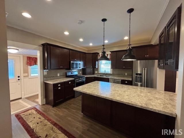 kitchen with dark wood-type flooring, decorative light fixtures, appliances with stainless steel finishes, and sink