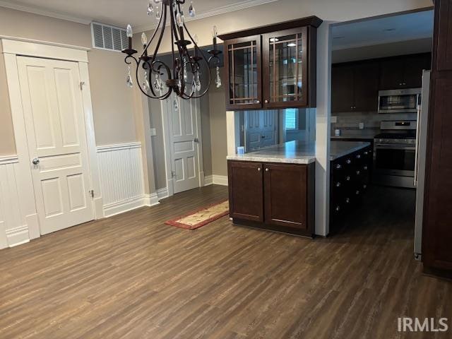 kitchen featuring stainless steel appliances, dark hardwood / wood-style flooring, crown molding, an inviting chandelier, and dark brown cabinets