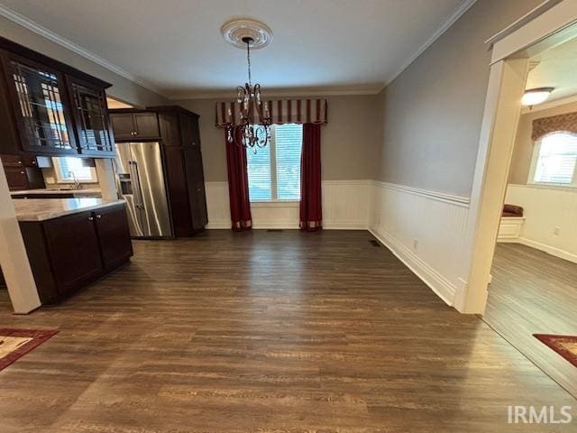 unfurnished dining area with ornamental molding, sink, a chandelier, and dark hardwood / wood-style flooring