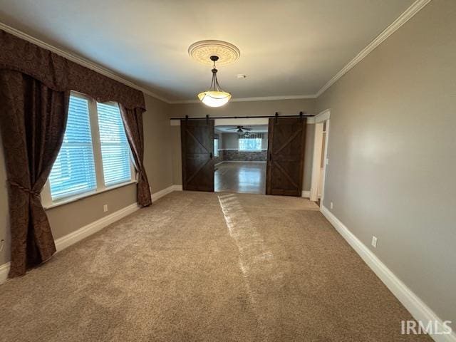 carpeted empty room with ceiling fan, ornamental molding, and a barn door