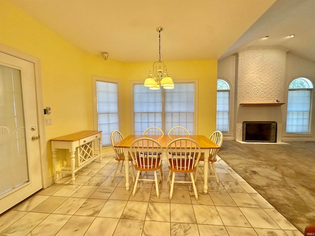 dining area featuring a fireplace, vaulted ceiling, and an inviting chandelier