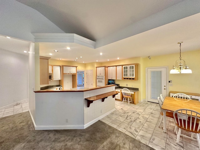 kitchen with light carpet, kitchen peninsula, hanging light fixtures, a kitchen bar, and white oven