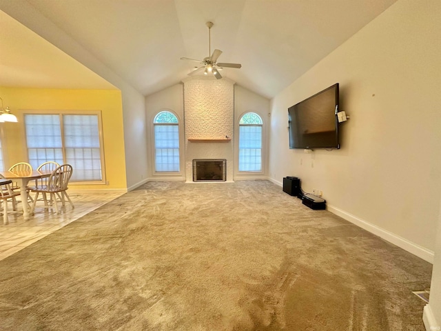 unfurnished living room featuring a fireplace, vaulted ceiling, carpet flooring, and ceiling fan