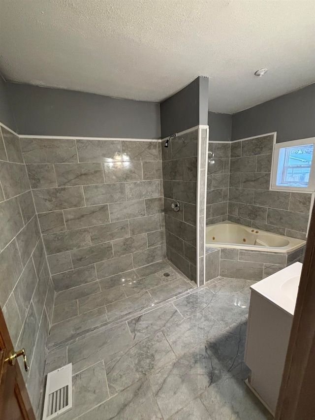 bathroom featuring shower with separate bathtub, vanity, and a textured ceiling