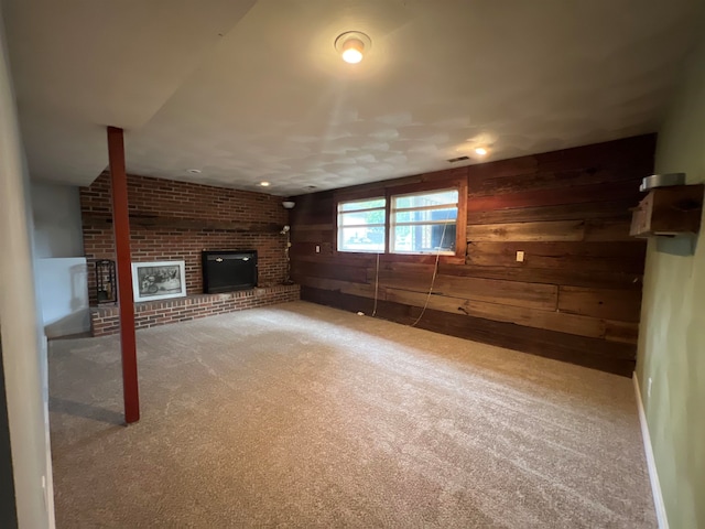 unfurnished living room featuring carpet floors, a brick fireplace, and wood walls