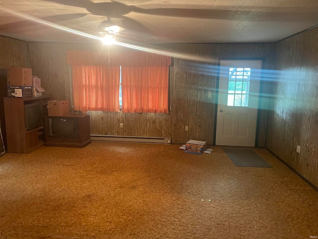 interior space featuring ceiling fan, carpet, wood walls, and a baseboard heating unit