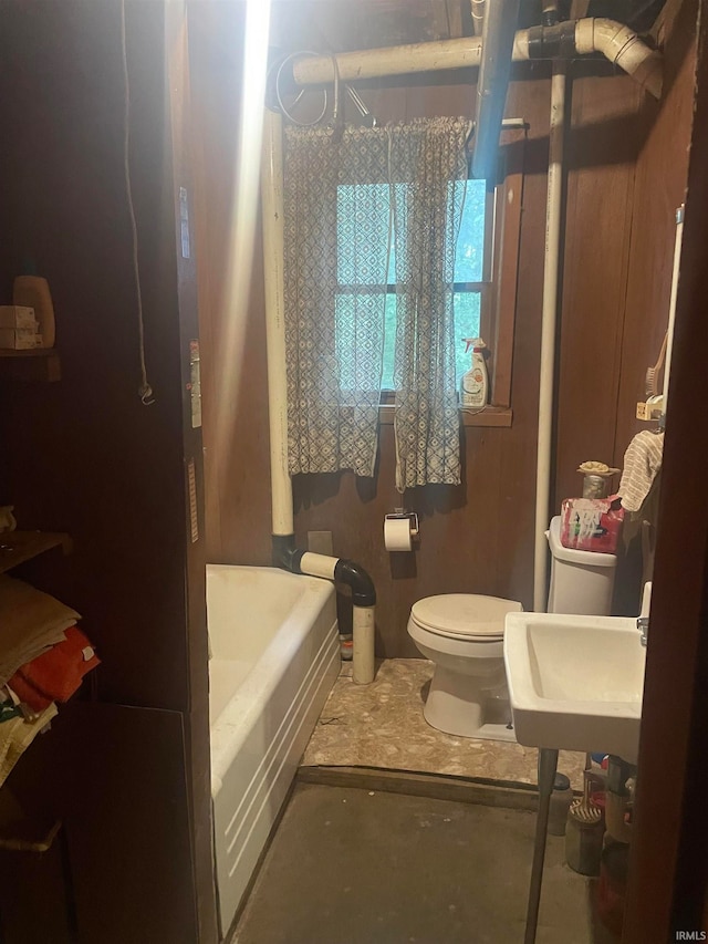 bathroom featuring a washtub, sink, and toilet