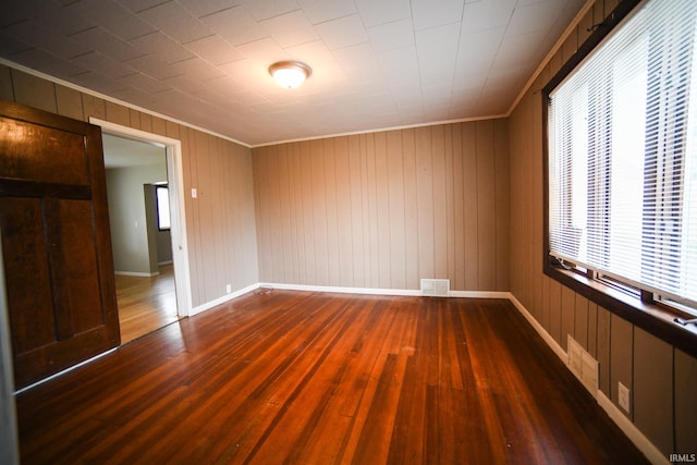 unfurnished bedroom with wood walls, crown molding, and dark hardwood / wood-style flooring