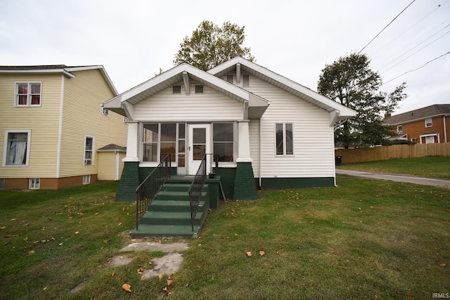 back of property featuring a sunroom and a lawn