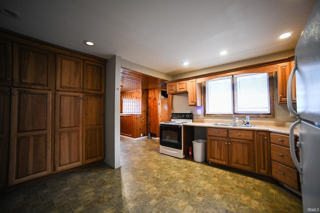 kitchen with electric stove, stainless steel fridge, and sink