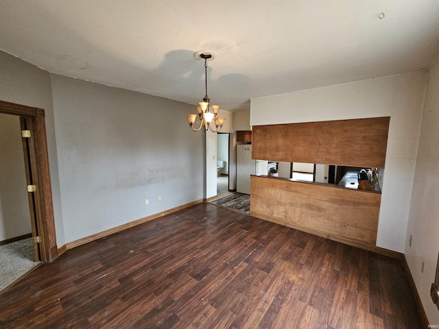 kitchen featuring dark wood-type flooring, refrigerator, an inviting chandelier, and kitchen peninsula