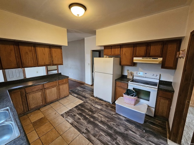 kitchen featuring white appliances, dark tile patterned flooring, and sink