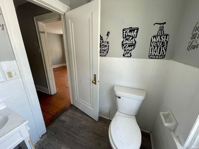 bathroom featuring vanity, tile walls, hardwood / wood-style floors, and toilet