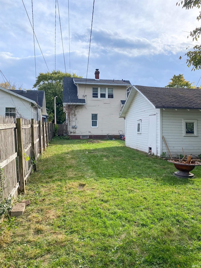 back of property featuring a lawn and an outdoor fire pit