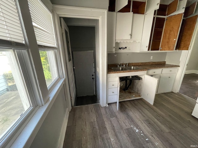 kitchen featuring built in desk, dark wood-type flooring, sink, and white cabinets