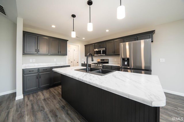 kitchen featuring an island with sink, stainless steel appliances, baseboards, and dark wood-type flooring
