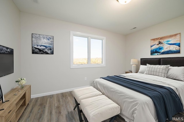 bedroom with wood finished floors, visible vents, and baseboards