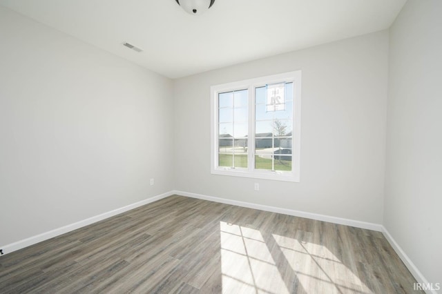 unfurnished room featuring wood finished floors, visible vents, and baseboards