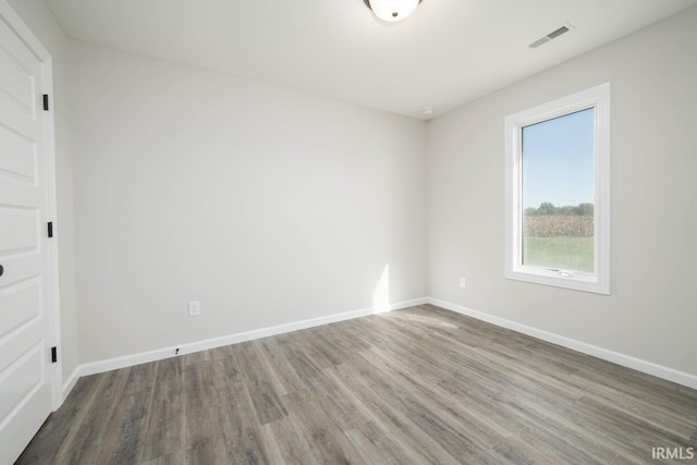 spare room with visible vents, baseboards, and wood finished floors
