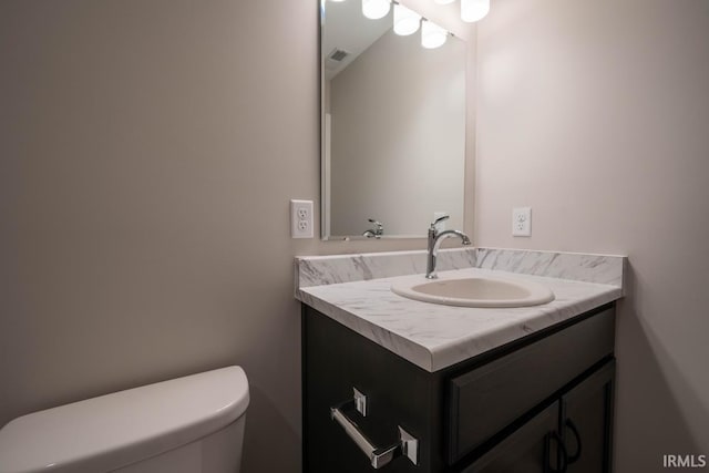 half bathroom featuring visible vents, vanity, and toilet