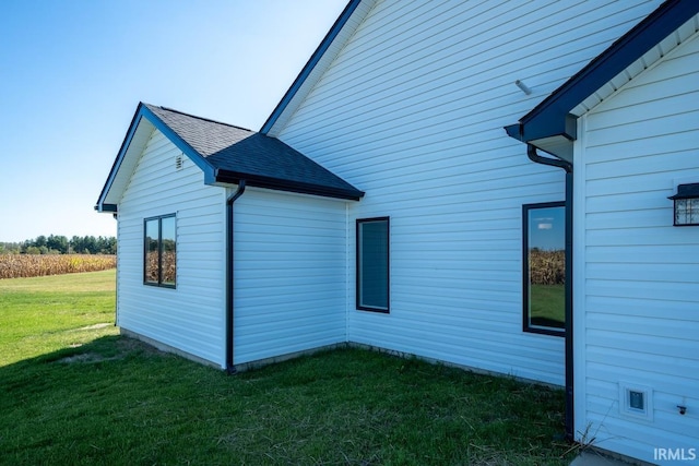 view of home's exterior with a lawn and roof with shingles