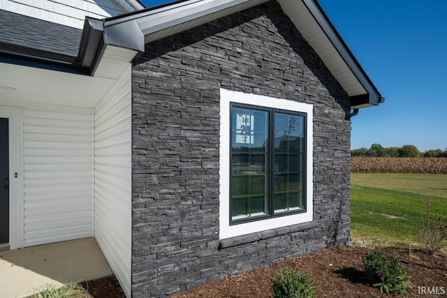 view of home's exterior featuring stone siding and a lawn