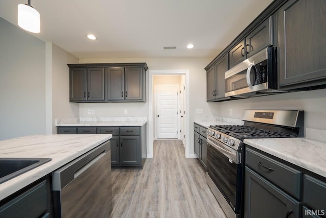 kitchen with light hardwood / wood-style floors, dark brown cabinetry, decorative light fixtures, and stainless steel appliances