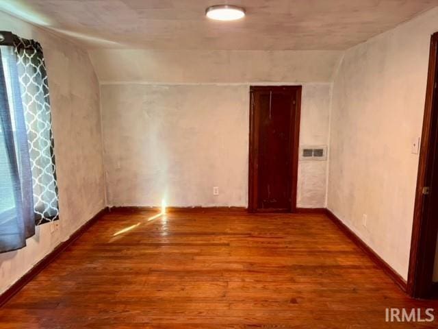 empty room featuring lofted ceiling and wood-type flooring