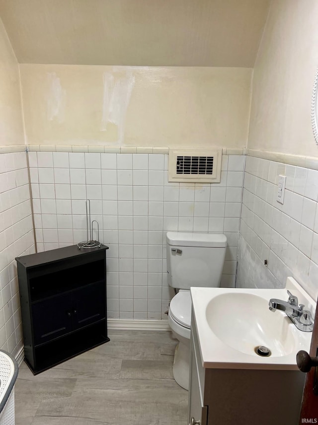 bathroom featuring tile walls, hardwood / wood-style floors, vanity, and toilet