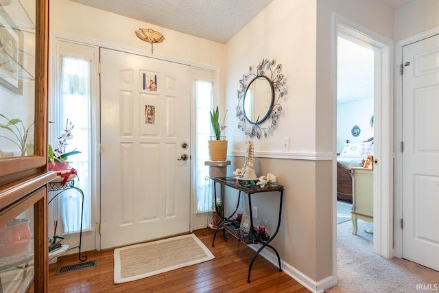 entryway with a textured ceiling, plenty of natural light, and light hardwood / wood-style floors