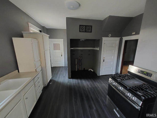 kitchen featuring dark hardwood / wood-style floors, stainless steel gas stove, sink, white refrigerator, and white cabinetry