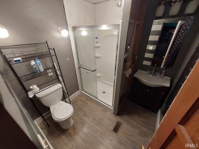 bathroom featuring wood-type flooring, vanity, toilet, and an enclosed shower