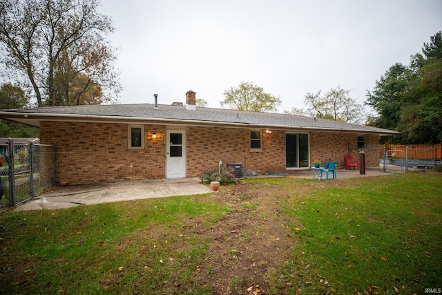 rear view of house featuring a lawn and a patio