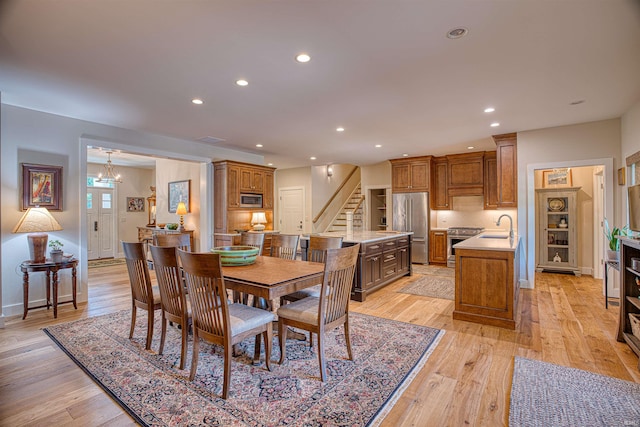 dining room with an inviting chandelier, sink, and light hardwood / wood-style floors