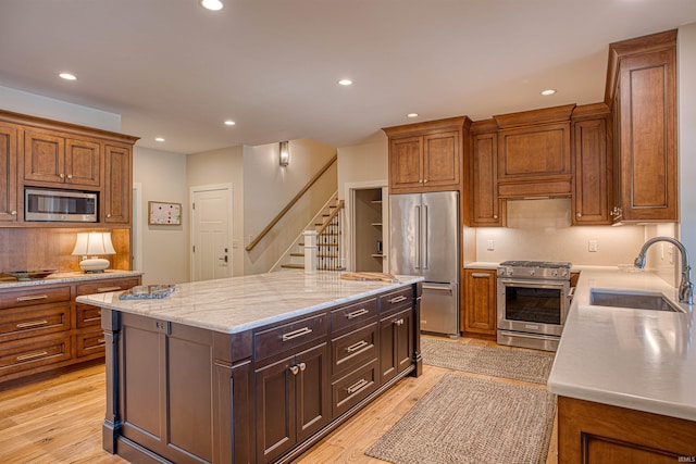 kitchen featuring light wood-type flooring, built in appliances, a center island, and sink