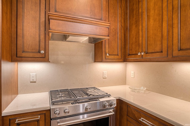 kitchen featuring light stone countertops, stainless steel range, and premium range hood