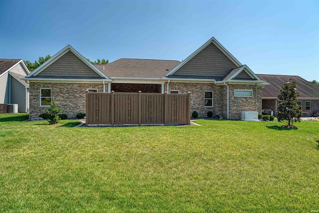 back of property with central AC unit and a lawn