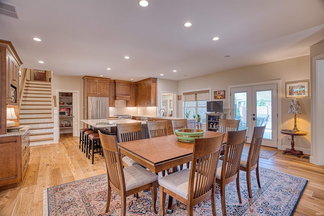 dining area with french doors and light hardwood / wood-style flooring