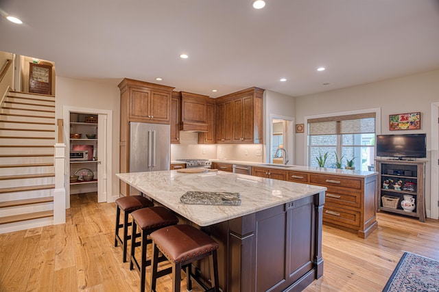 kitchen with appliances with stainless steel finishes, light wood-type flooring, sink, and a center island