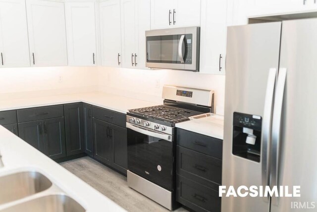 kitchen featuring appliances with stainless steel finishes, light hardwood / wood-style flooring, and white cabinetry