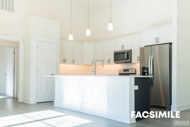 kitchen with appliances with stainless steel finishes, white cabinetry, decorative light fixtures, and light hardwood / wood-style floors