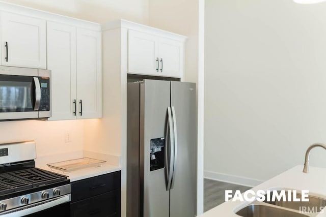 kitchen featuring hardwood / wood-style flooring, stainless steel appliances, sink, and white cabinetry