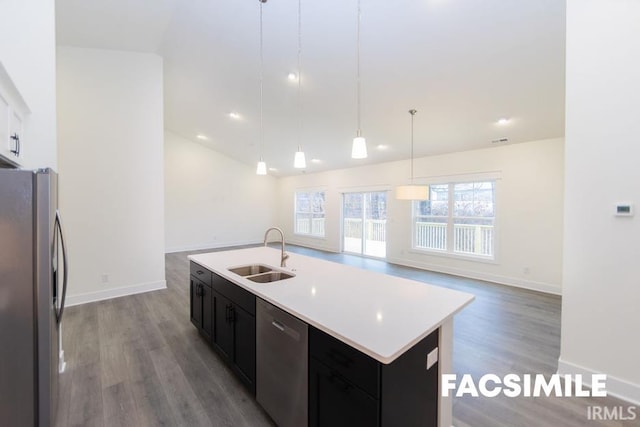 kitchen featuring pendant lighting, sink, a kitchen island with sink, appliances with stainless steel finishes, and light wood-type flooring