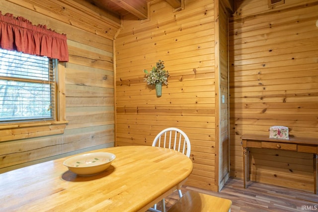 dining room with hardwood / wood-style flooring, beam ceiling, and wood walls