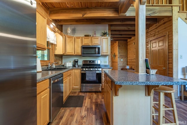 kitchen featuring a kitchen island, wooden walls, beamed ceiling, dark wood-type flooring, and appliances with stainless steel finishes