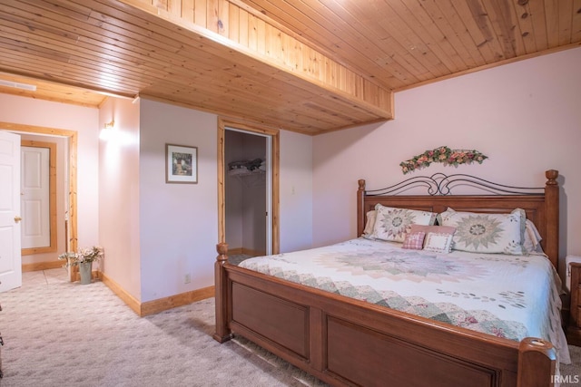 bedroom featuring a closet, wood ceiling, a walk in closet, and light colored carpet