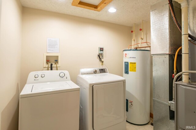 washroom featuring water heater, washer and clothes dryer, a textured ceiling, and heating unit