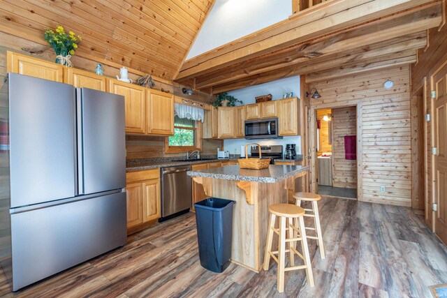 kitchen featuring dark hardwood / wood-style flooring, appliances with stainless steel finishes, high vaulted ceiling, wood walls, and a center island