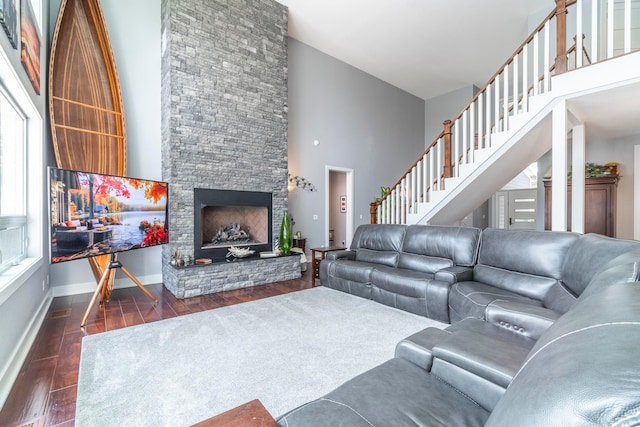 living room with a stone fireplace, dark hardwood / wood-style flooring, and high vaulted ceiling